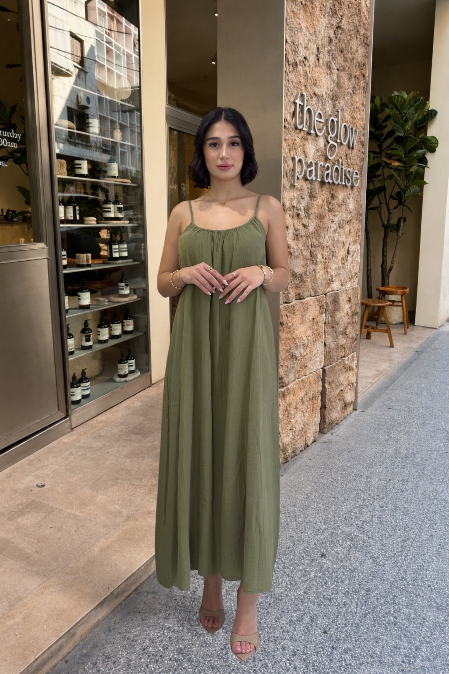 Woman in a green dress standing in front of a store entrance with 'The Glow Paradise' sign.