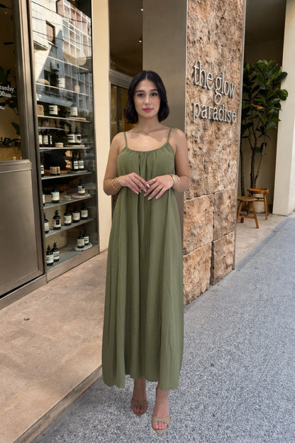 Woman in a green dress standing in front of a store entrance with 'The Glow Paradise' sign.