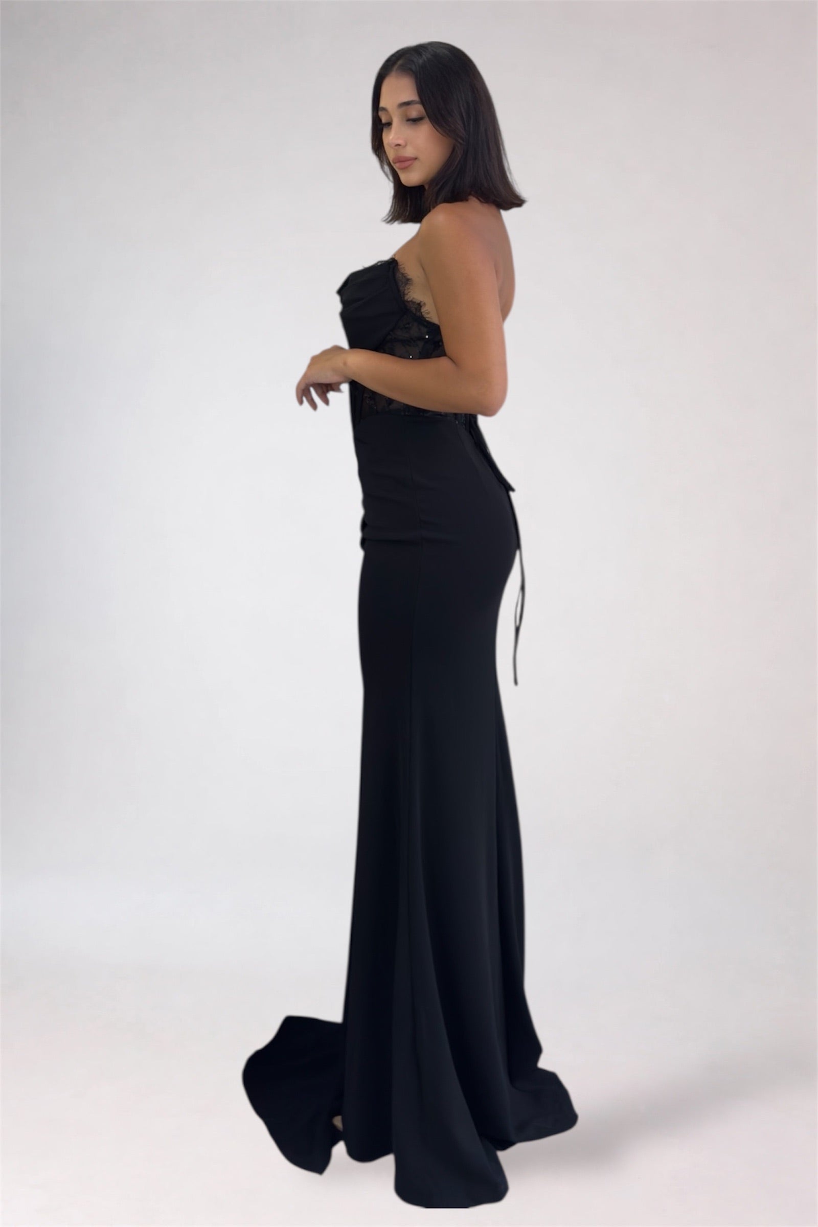 Woman wearing a black strapless gown on a white background