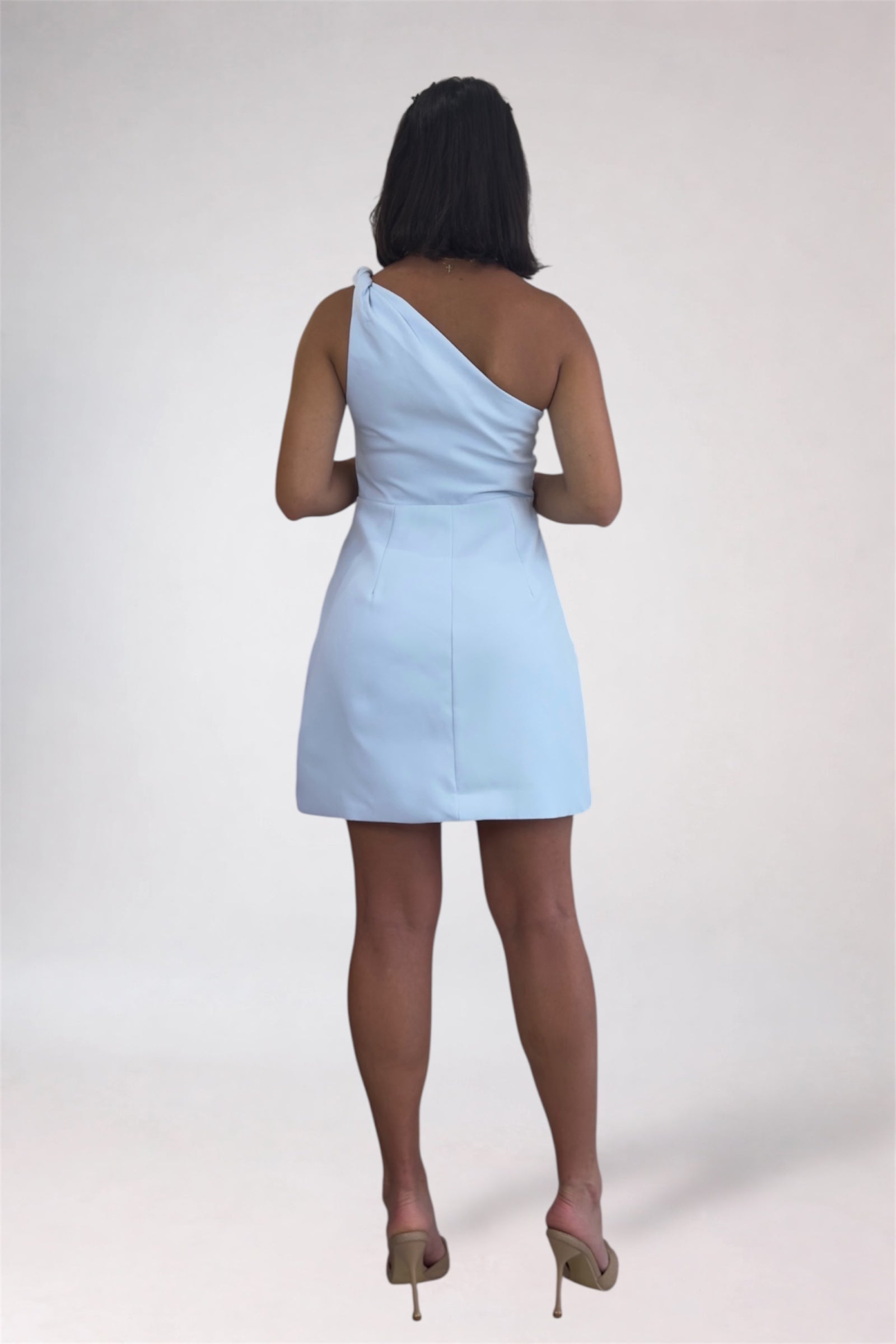 Woman wearing a light blue one-shoulder dress on a white background