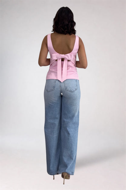 Woman wearing a pink sleeveless top and blue jeans on a white background