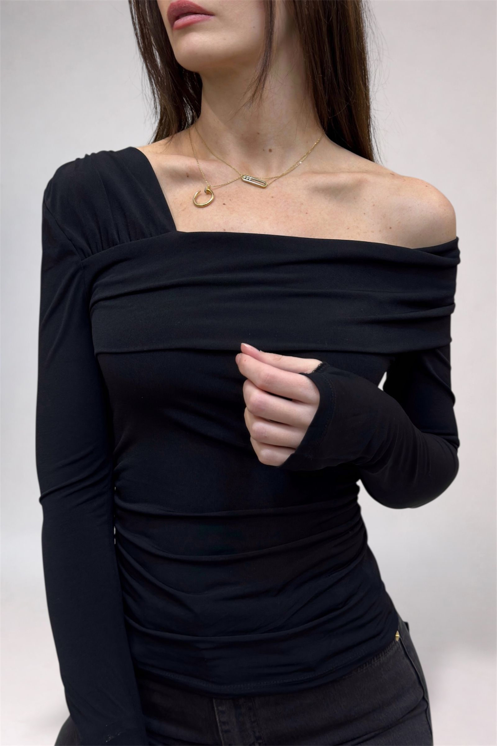 Woman wearing a black off-shoulder top against a white background