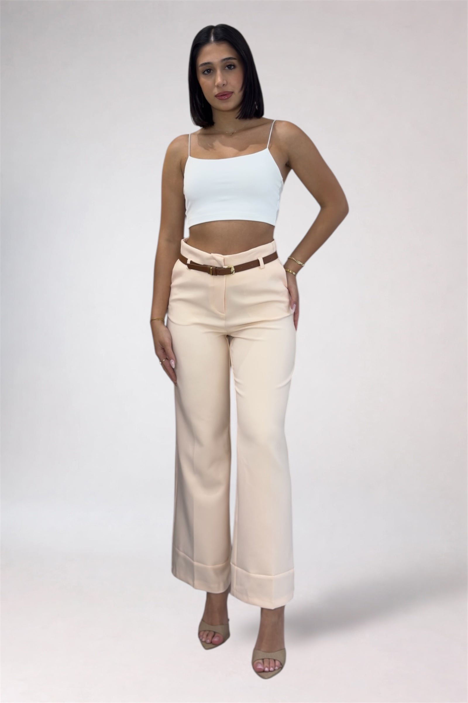Woman wearing a light blue top and beige pants on a white background