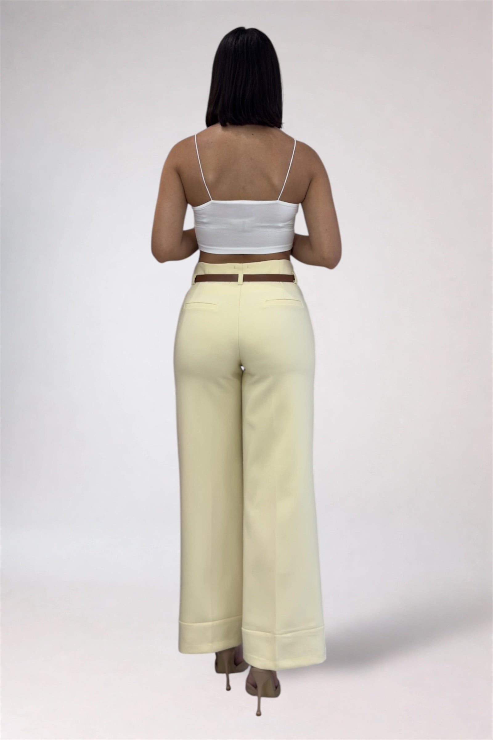 Person wearing a white top and beige pants on a plain background