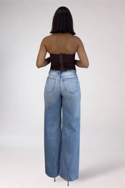 Person wearing high-waisted blue jeans and a strapless top on a white background