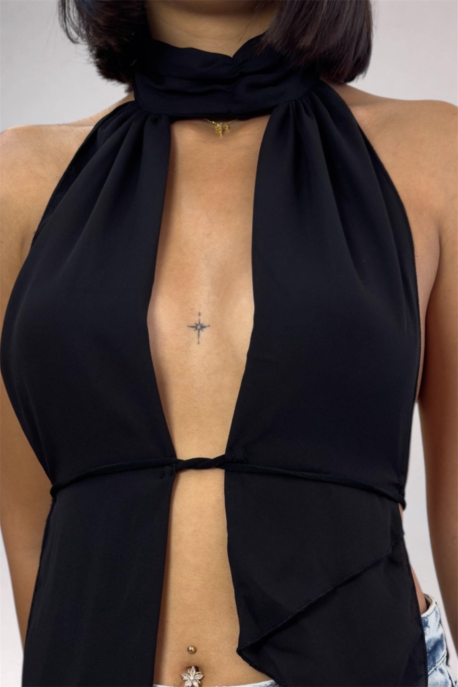 Black halter top with open back worn by a person on a neutral background