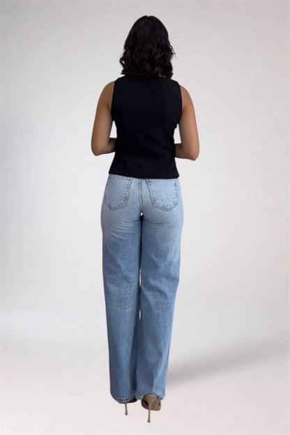 Person wearing light blue jeans and a black sleeveless top on a white background