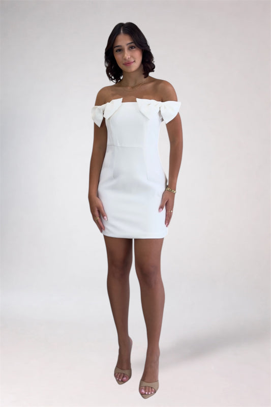 Woman wearing a white off-shoulder dress against a plain background