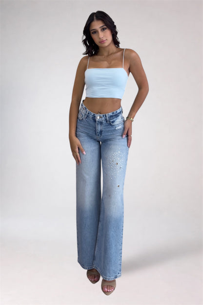 Woman wearing a light blue crop top and high-waisted jeans on a white background