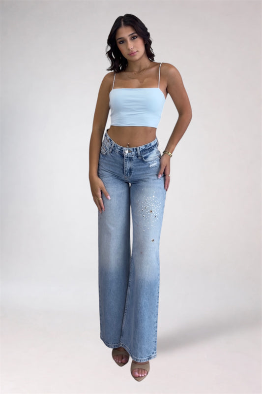 Woman wearing a light blue crop top and high-waisted jeans on a white background