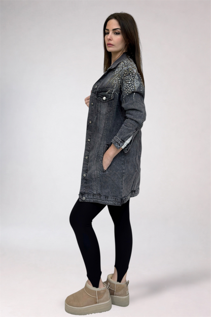 Woman wearing a long denim jacket with studded details on a white background