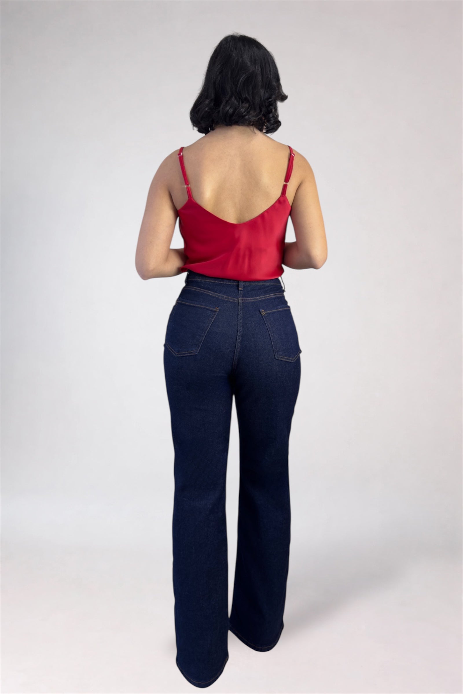Person wearing a red top and dark blue jeans on a white background