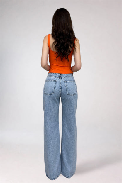 Person wearing an orange tank top and light blue jeans on a white background