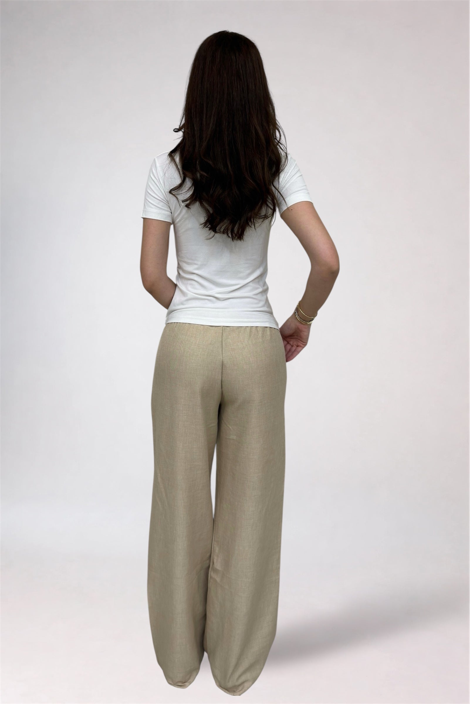 Person wearing a white shirt and beige pants on a plain background