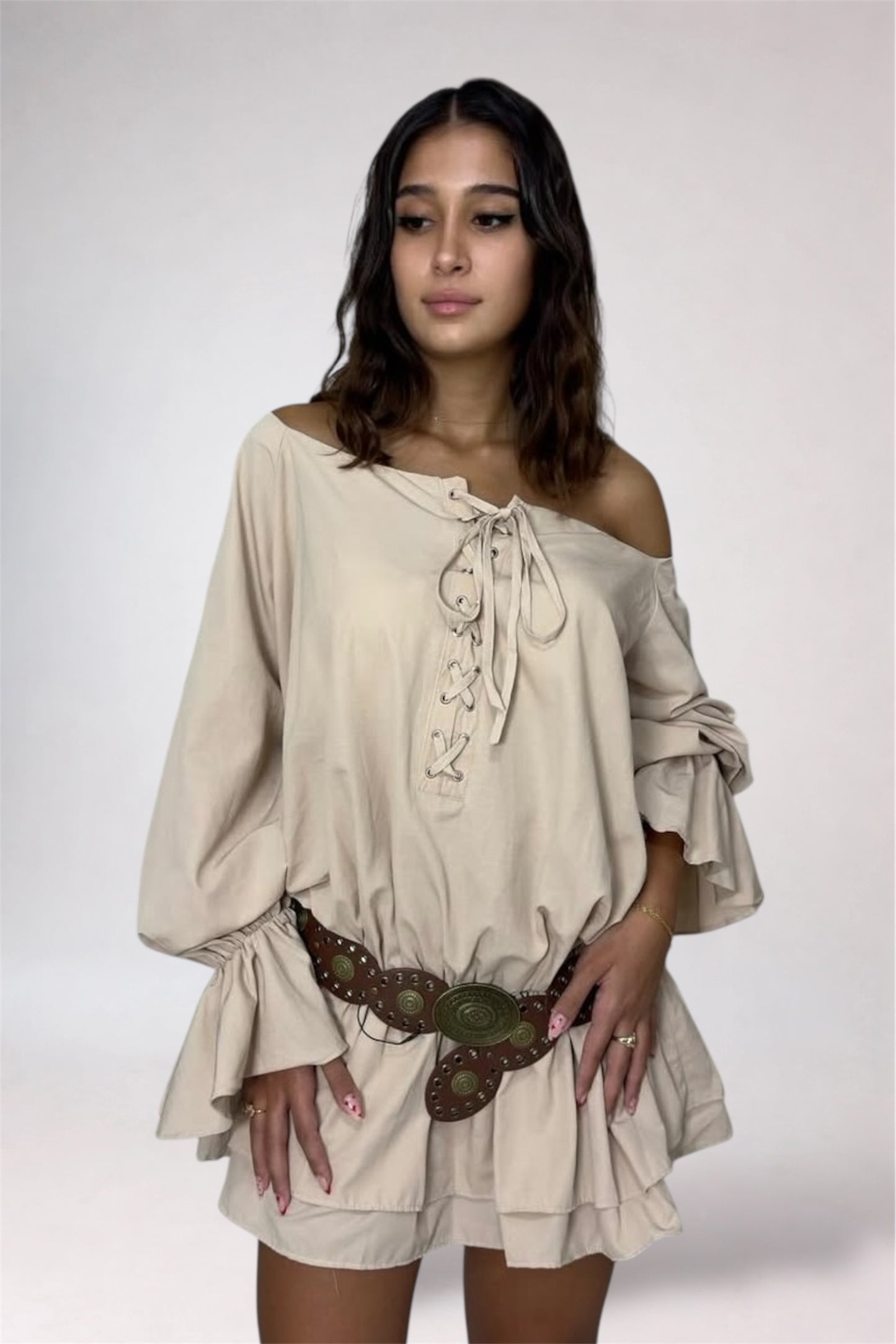 Woman wearing a beige off-shoulder dress with long sleeves on a white background