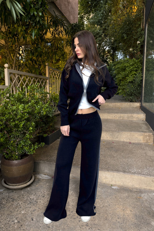 Woman in black outfit standing against a hedge