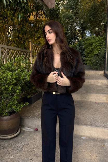 Woman wearing a fur coat and black outfit on outdoor steps