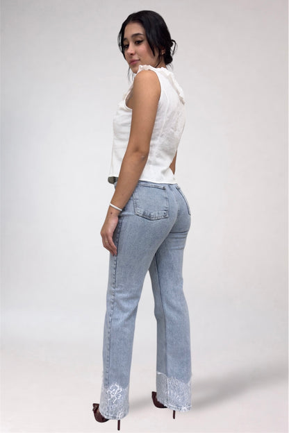 Woman wearing light blue jeans and a white top on a plain background