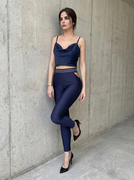 Woman in a navy blue outfit standing against a concrete wall.
