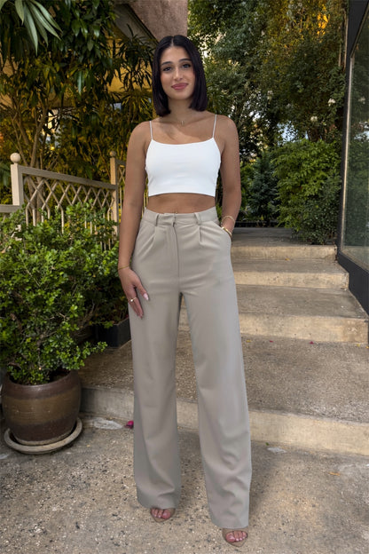 Woman wearing a white top and beige pants standing outdoors on steps.