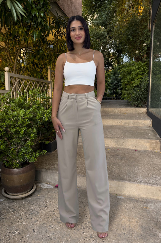 Woman wearing a white top and beige pants standing outdoors on steps.