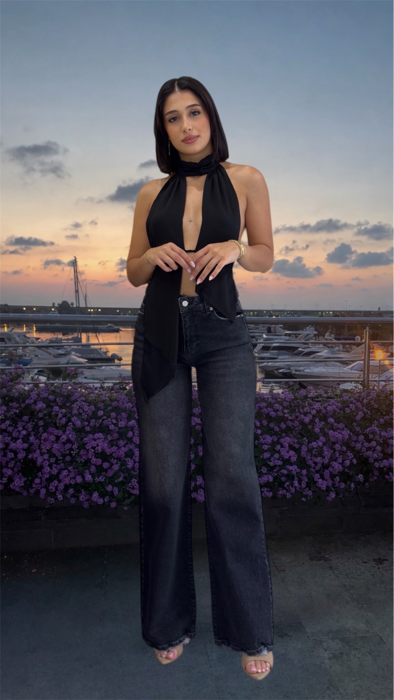 Woman wearing a black sleeveless top and dark blue jeans in nature