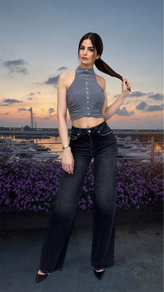 Woman wearing a gray halter top and black high-waisted jeans in nature