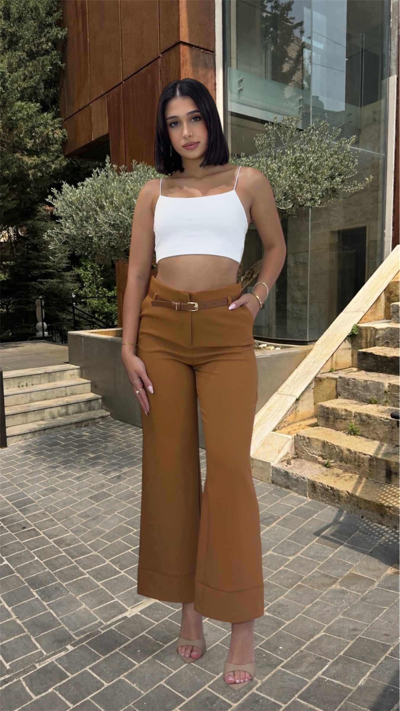 Woman wearing a white top and brown high-waisted pants 