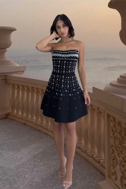 Woman in a strapless black and white dress standing on a balcony with a scenic background.